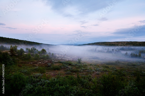 road goes into the distance through the hills through the fog. Concept travel around Russia. Teriberka, Kola Peninsula, Russia.