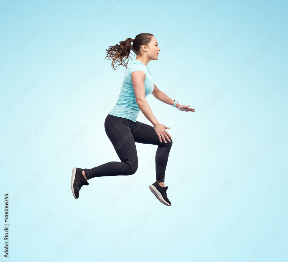 Obraz premium happy smiling sporty young woman jumping in air