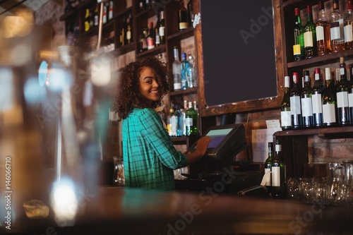 Portrait of beautiful female bar tender using electronic machine