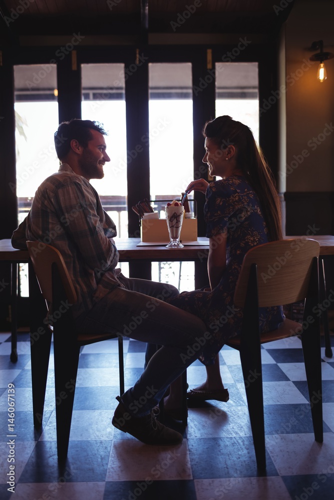 Happy couple interacting while having milkshake Happy couple interacting while having milkshake