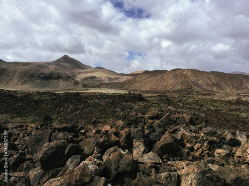 Beautiful view overlooking rusty red desert, distant mountains in Fuerteventura island, Canaries, Spain