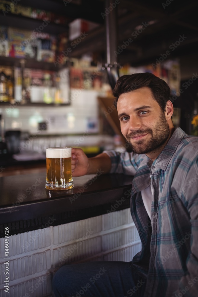 Portrait of happy man having beer at counter