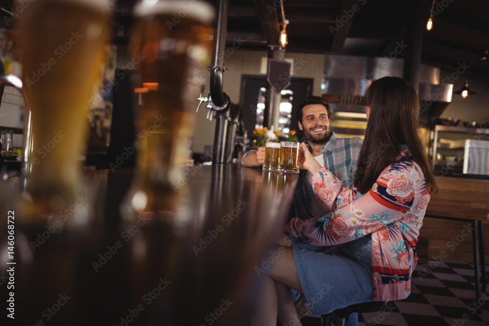 Obraz premium Happy couple interacting while having beer at counter