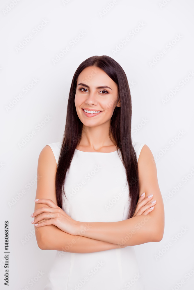 Close up portrait of young successful girl in white dress on white background standing with crossed arms and smiling Close up portrait of young successful girl in white dress on white background standing with crossed arms and smiling