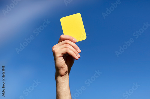 referee on football field showing yellow card