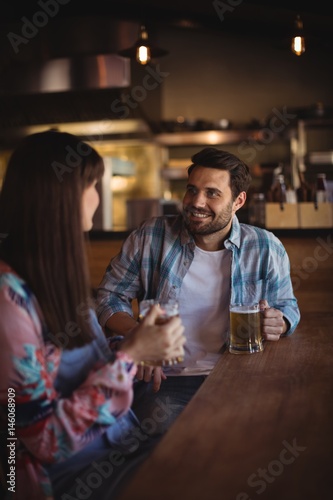 Couple interacting while having beer at counter