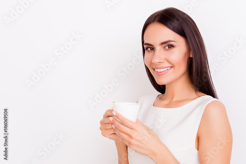 Close up portrait of young successful businesslady on a coffee break, she is resting and enjoying the drink. Woman is on a white background, she is smiling