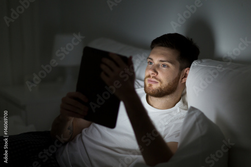 young man with tablet pc in bed at home bedroom