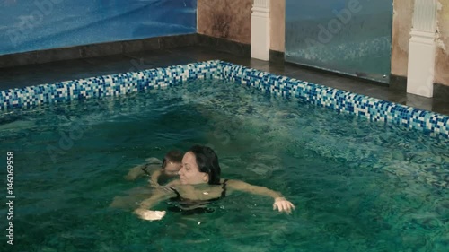 Happy mother teaching to son in swimming pool 4k