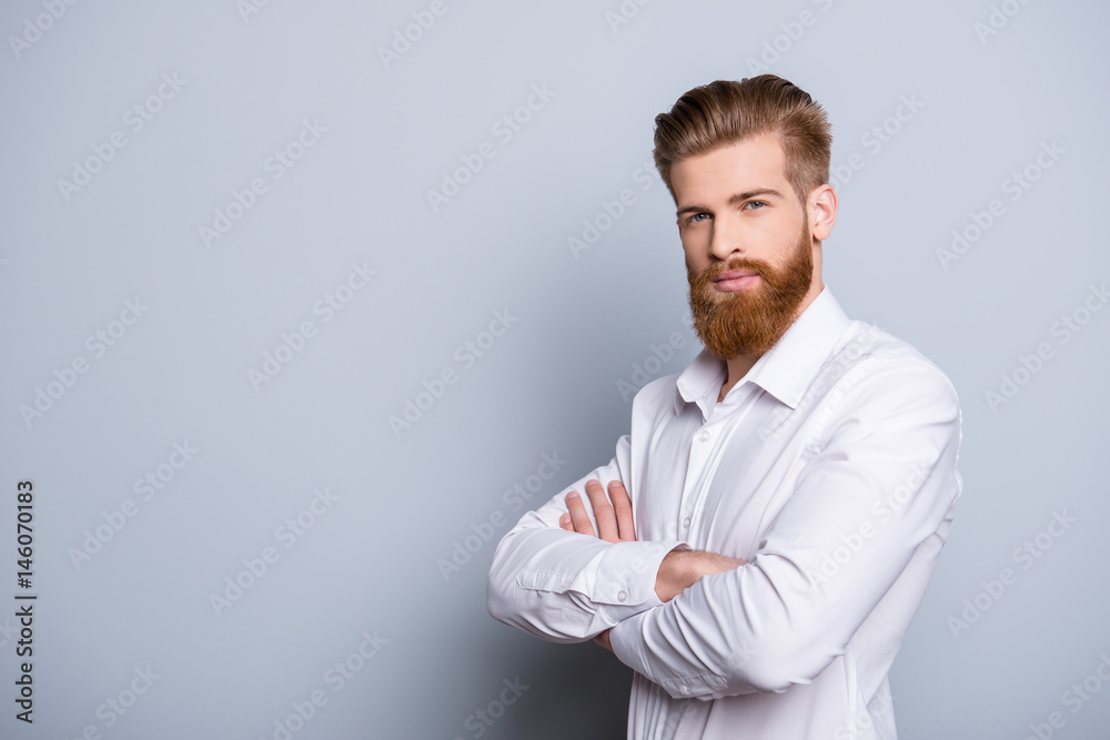 Half-profile portrait of serious confident bearded man keeping crossed hands near copy space and looking at camera Half-profile portrait of serious confident bearded man keeping crossed hands near copy space and looking at camera