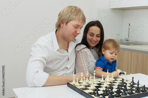 Family playing chess on a table at home