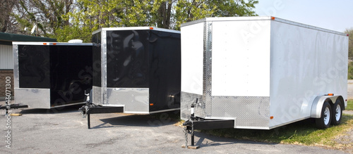 Three black and white transport trailers in a row. photo