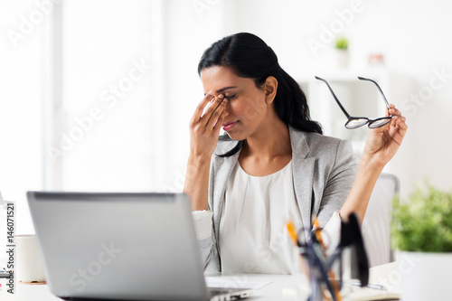 businesswoman rubbing tired eyes at office photo