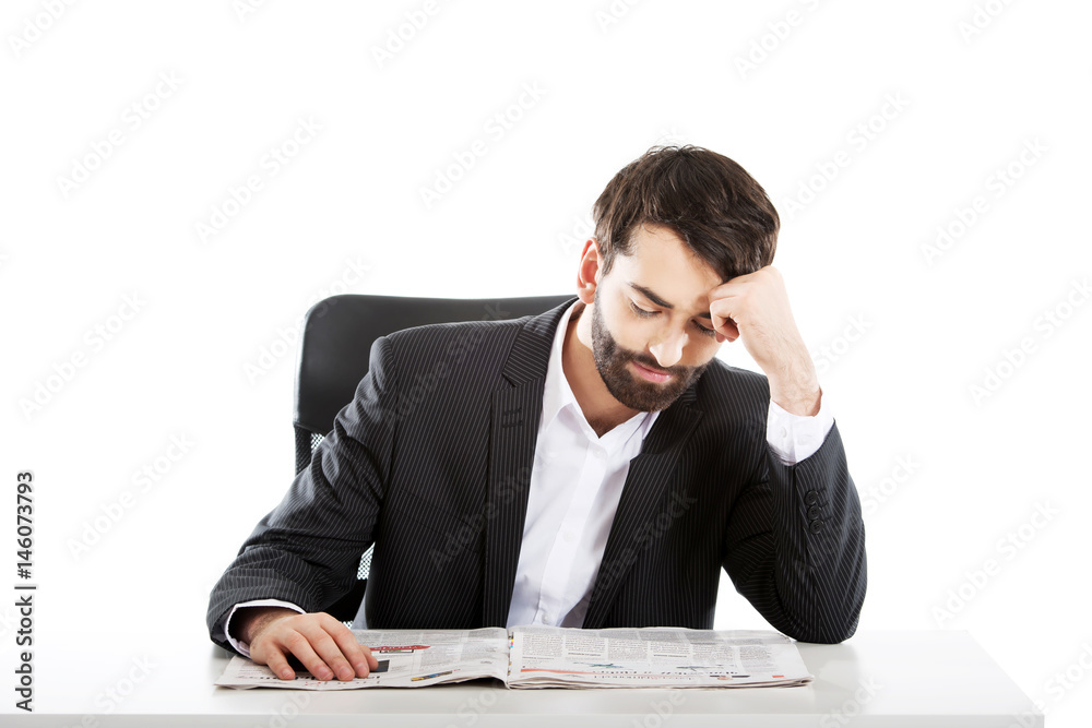 Young man reading newspaper in the office. Young man reading newspaper in the office.