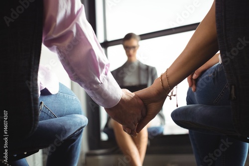 Mid section of couple holding hands