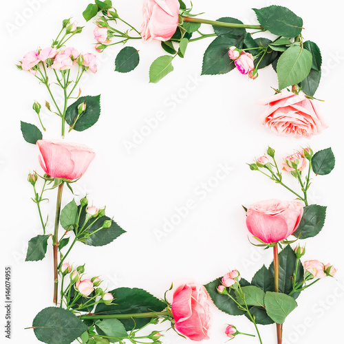 Flat lay floral frame made of pink roses, leaves and buds on white background. Top view.