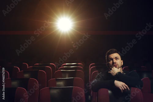 Handsome young man watching movie in theater