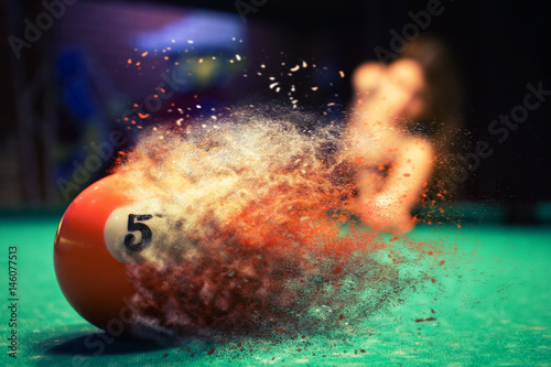 Orange billiard ball splits into particles and debris upon impact photo