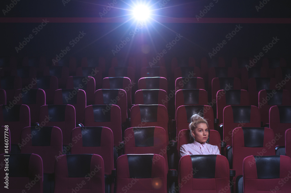 Blonde girl watching movie in empty theater