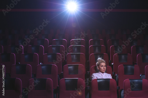 Blonde girl watching movie in empty theater