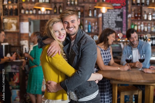Smiling young couple hugging in pub