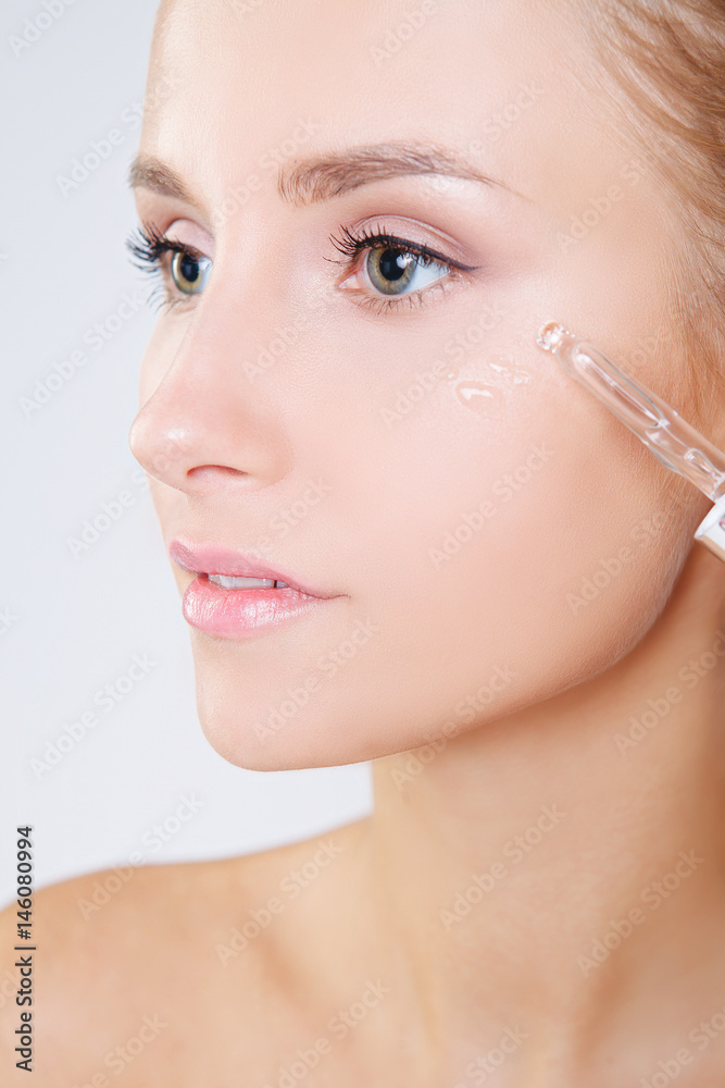 beautiful model applying a skin serum treatment on grey background. Perfect beautiful model applying a skin serum treatment on grey background. Perfect