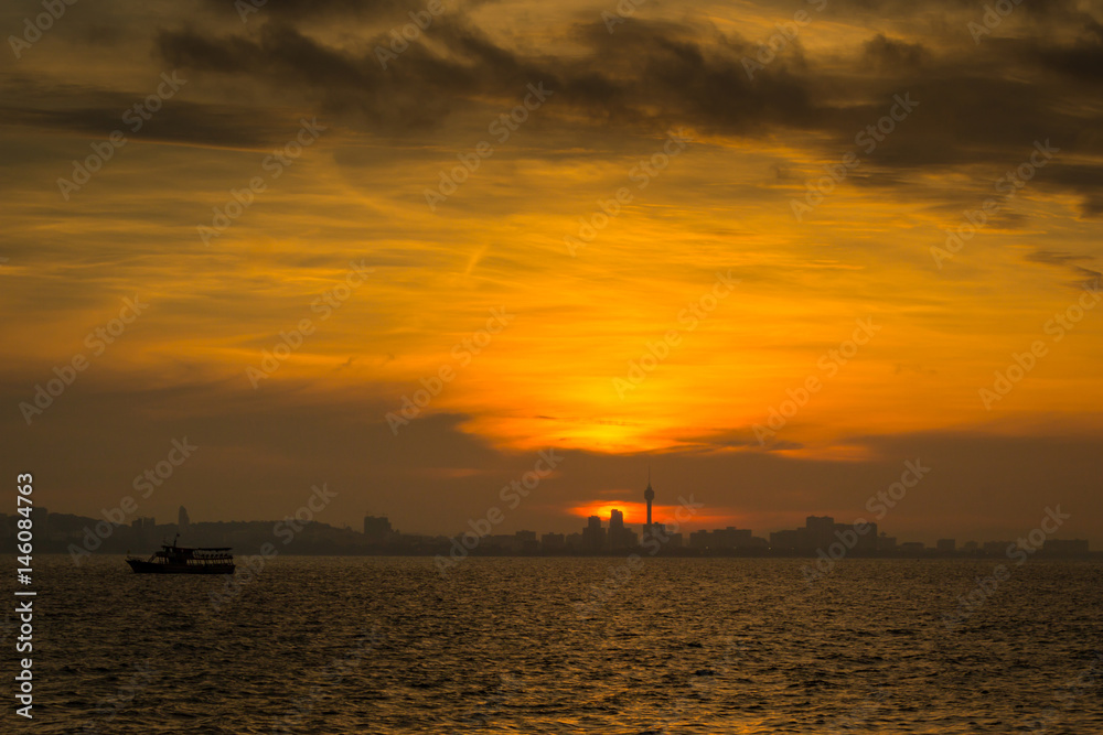 Sunset on the sea. Silhouette of city and fishing boat