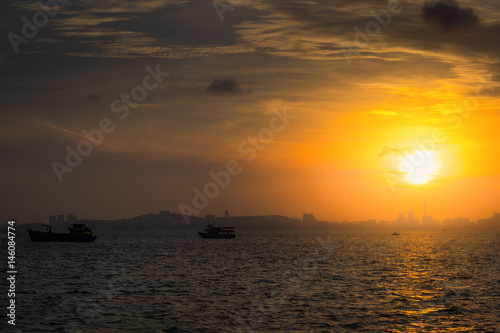 Sunset on the sea. Silhouette of city and fishing boat © Satawat