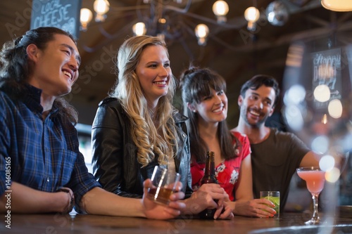 Smiling friends counter looking away in pub