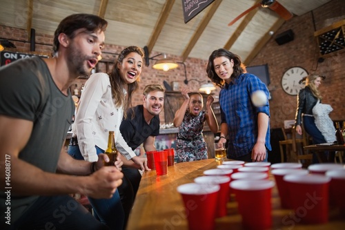 Young friends enjoying beer pong game in restaurant