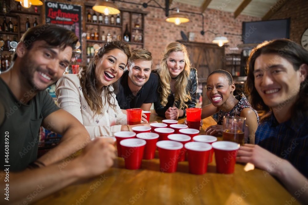 Portrait of smiling friends around disposable cups on table