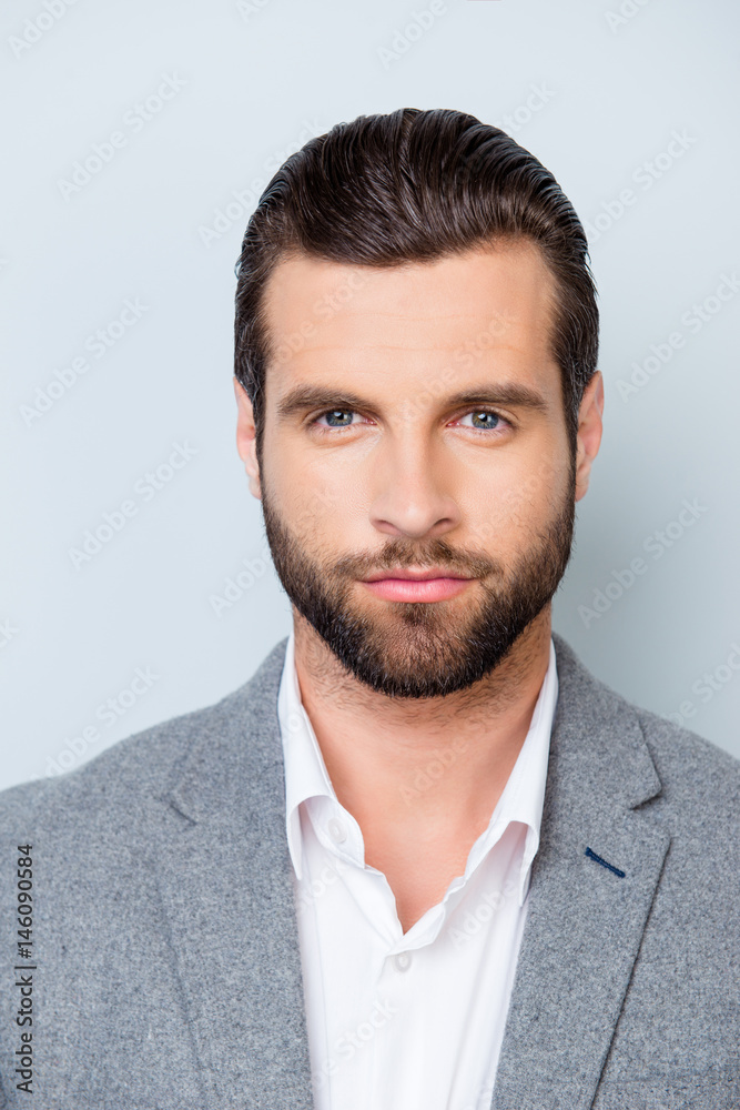 Vertical close up portrait of serious young minded man in white shirt and gray jacket on gray background Vertical close up portrait of serious young minded man in white shirt and gray jacket on gray background