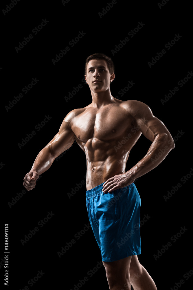 Fototapeta premium Muscular and fit young bodybuilder fitness male model posing over black background.