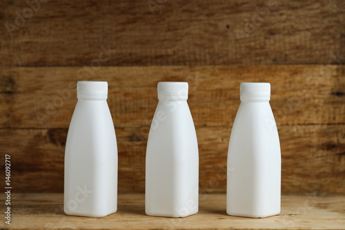 white plastic milk bottles on retro wooden table background