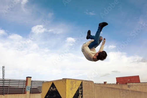 Young boy jumping somersault on the street.