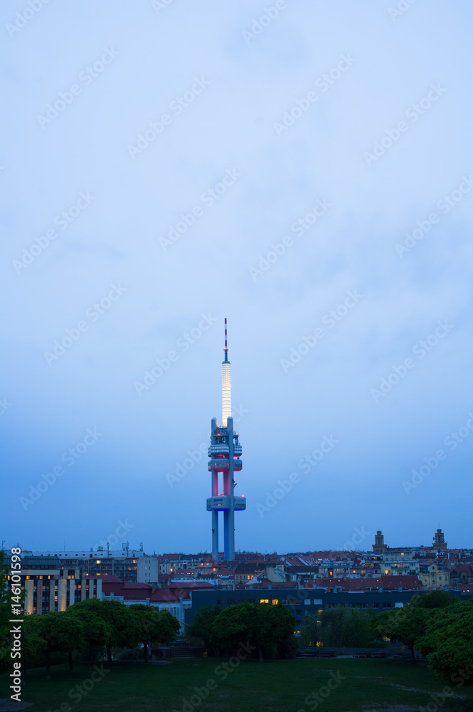 Horizon of Zizkov district in Prague, Czech Republic / Czechia - tall Zizkov television communications tower, transmitter and houses. View from Parukarka Park. Dark scenery in the evening.