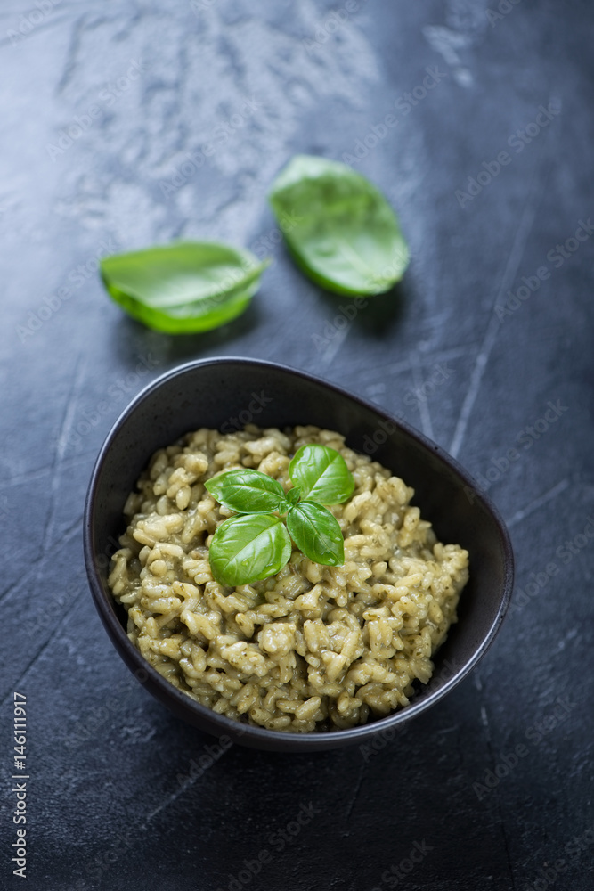 Spinach risotto on a dark grey stone background, elevated view, vertical shot Spinach risotto on a dark grey stone background, elevated view, vertical shot
