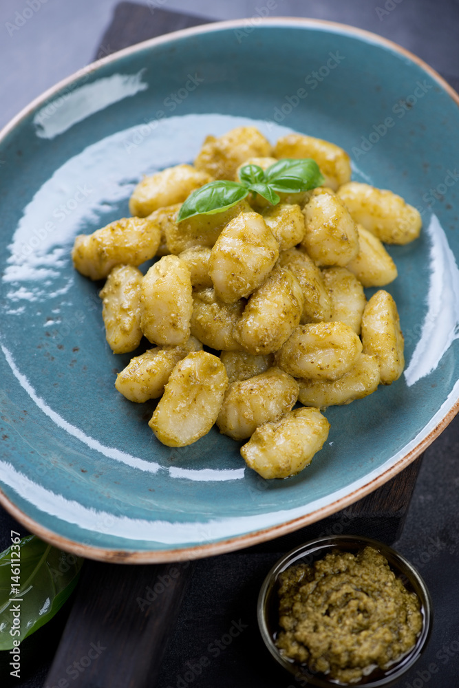 Close-up of potato gnocchi with basil pesto sauce served on a turquoise plate, studio shot Close-up of potato gnocchi with basil pesto sauce served on a turquoise plate, studio shot