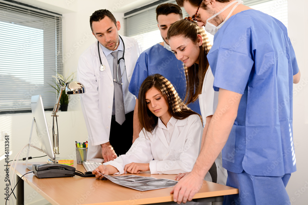 Obraz premium group of surgeons and medical professional staff discussing on patient radiography outside hospital operating room