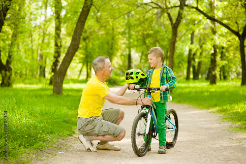 Grandfather gives his grandson a bicycle helmet