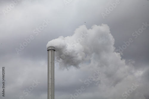 Low angle view of smoke emitting from chimney against cloudy sky