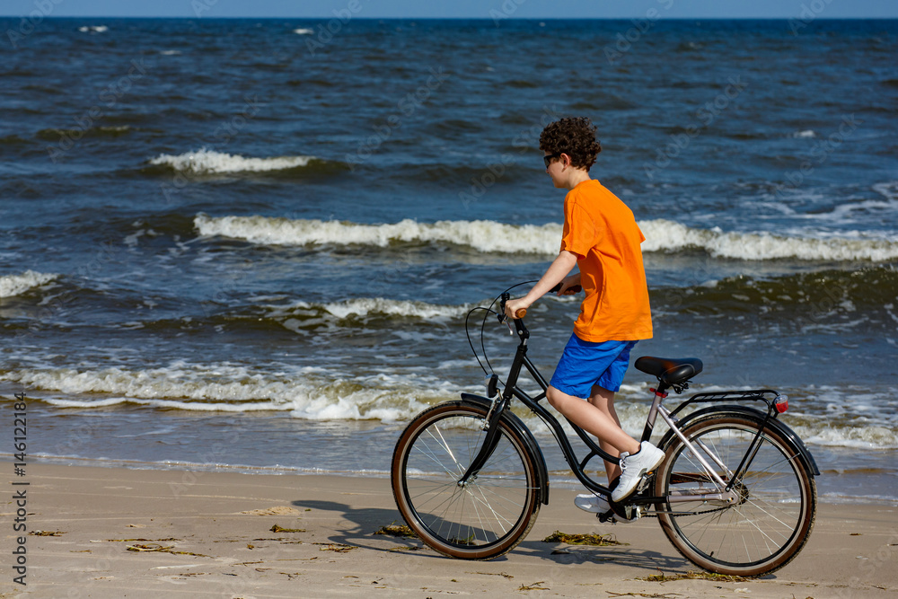 Fototapeta premium Teenage boy biking on beach