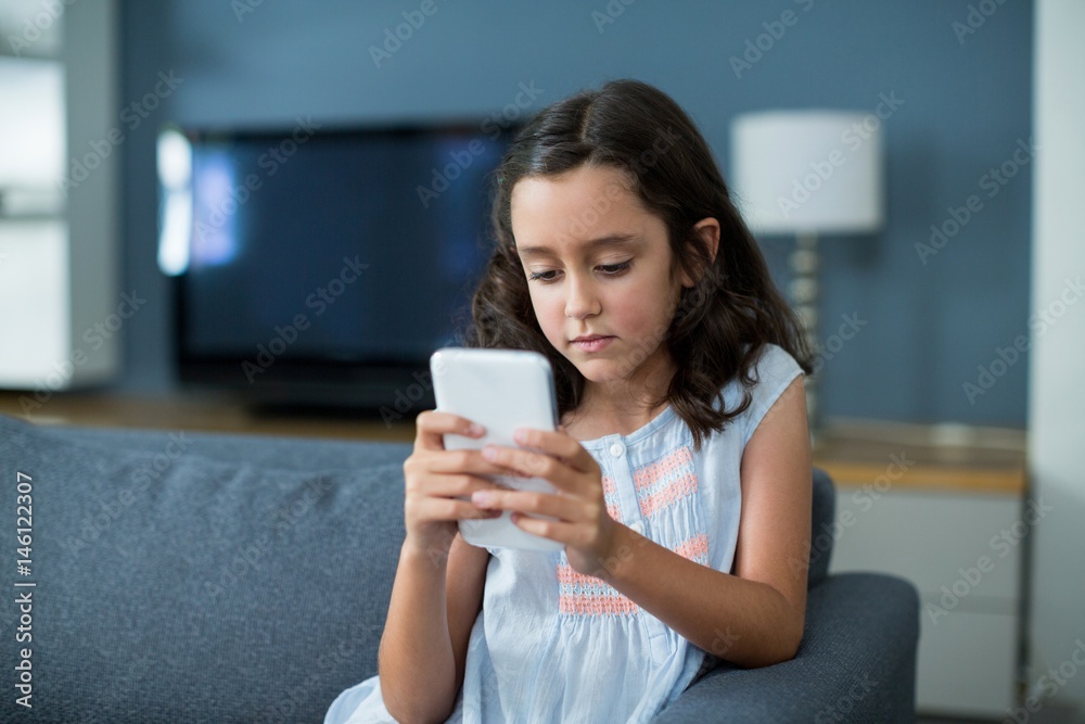 Girl sitting on sofa and using mobile phone Girl sitting on sofa and using mobile phone