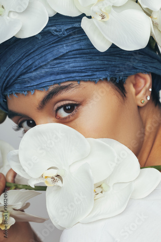 Fototapeta Portrait of woman hiding behind fresh white orchids