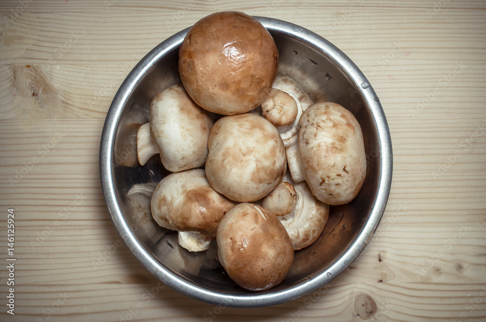 Champignon mushrooms in bowl on wooden kitchen desk table background. Top view. Flat lay mushrooms. Champignon mushrooms in bowl on wooden kitchen desk table background. Top view. Flat lay mushrooms.