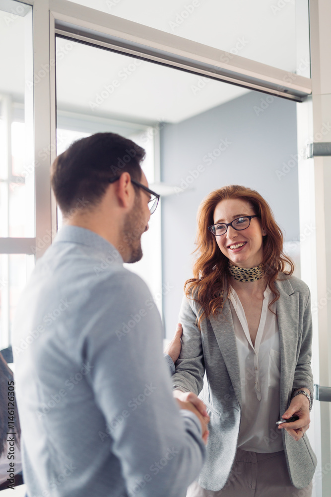 Business colleagues shaking hands after closing business deal