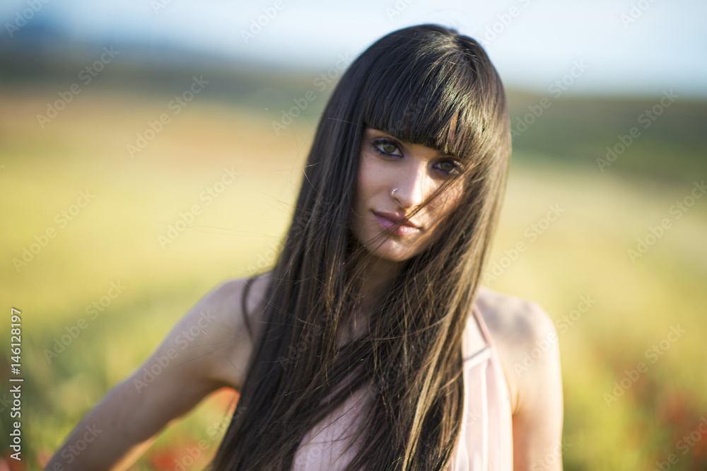 Portrait of a beautiful young woman outdoor in summer. Fields poppy.