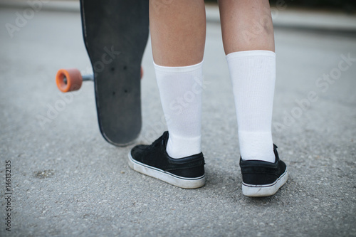 Young woman riding on her longboard. Detail of socks.