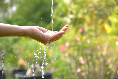 Water pouring in woman hand on nature background.