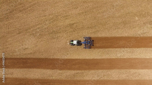 Fototapeta  aerial view of a tractor at work on agricultural fields - tractor cultivating a field in spring
